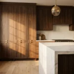Dark walnut kitchen cabinets with matte finish, brushed brass cup pulls, white marble waterfall island, herringbone backsplash, and brass globe pendant lights — 2026 modern kitchen cabinet trends