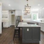 Mid-range kitchen remodel in Herndon VA featuring white shaker cabinets, gray island, quartz countertops, and hardwood flooring by Modern Kitchen & Bath
