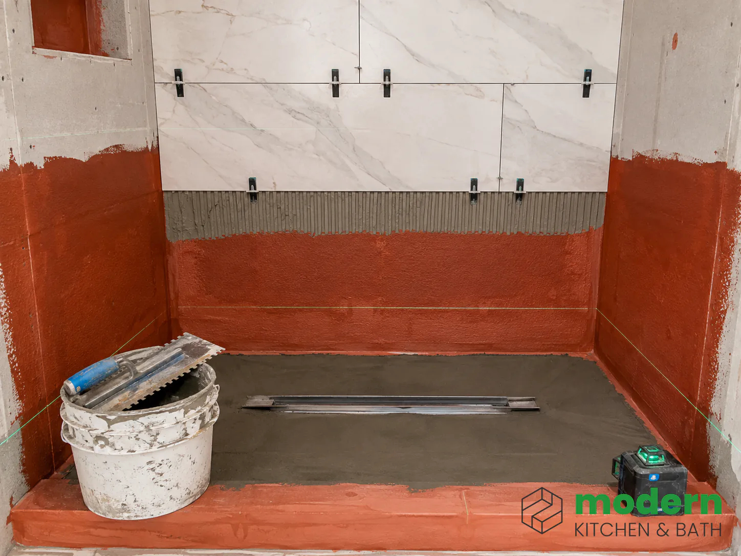 Custom tiled shower under construction with waterproofing membrane and sloped mortar pan